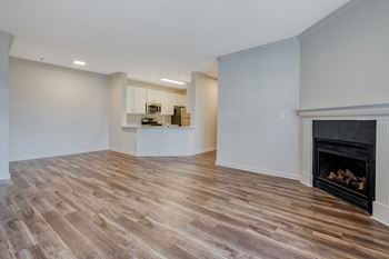 a living room with a fireplace and a kitchen in the background